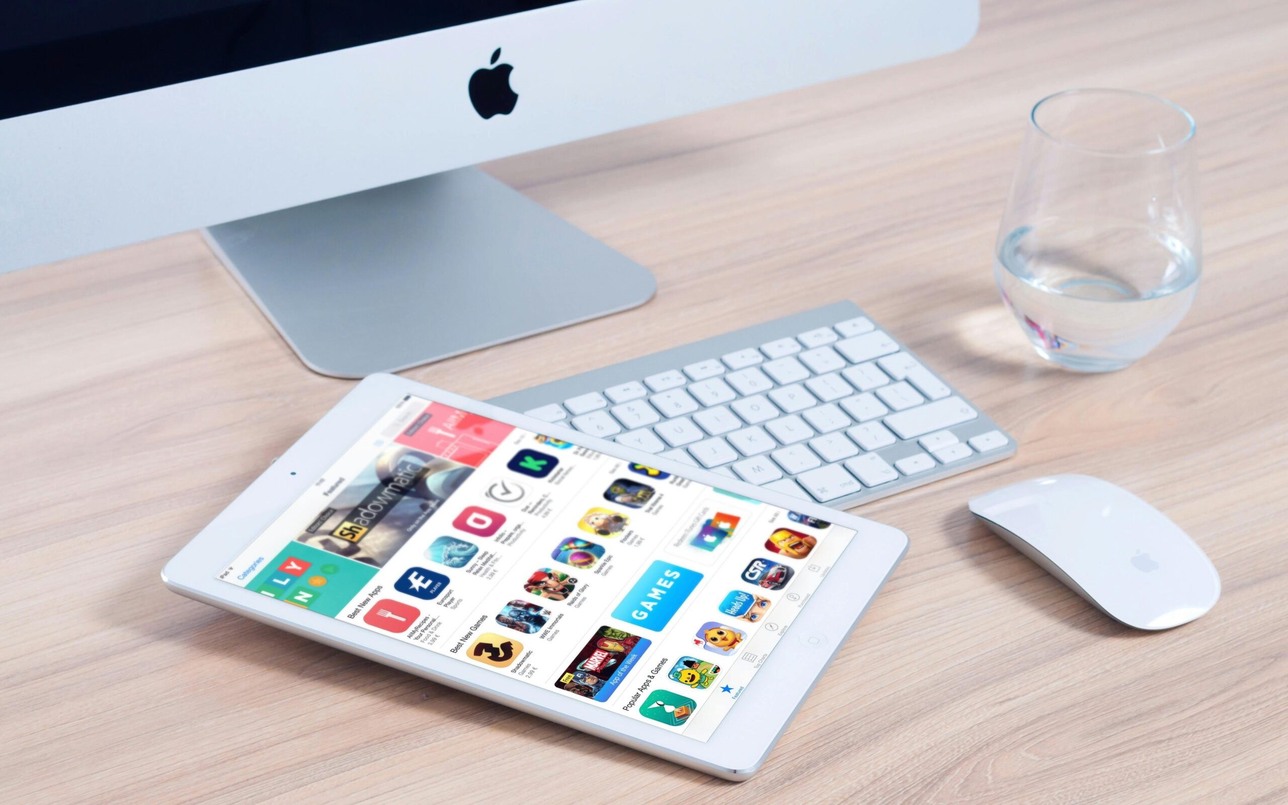 Sleek home office setup featuring an iMac and iPad showcasing apps.